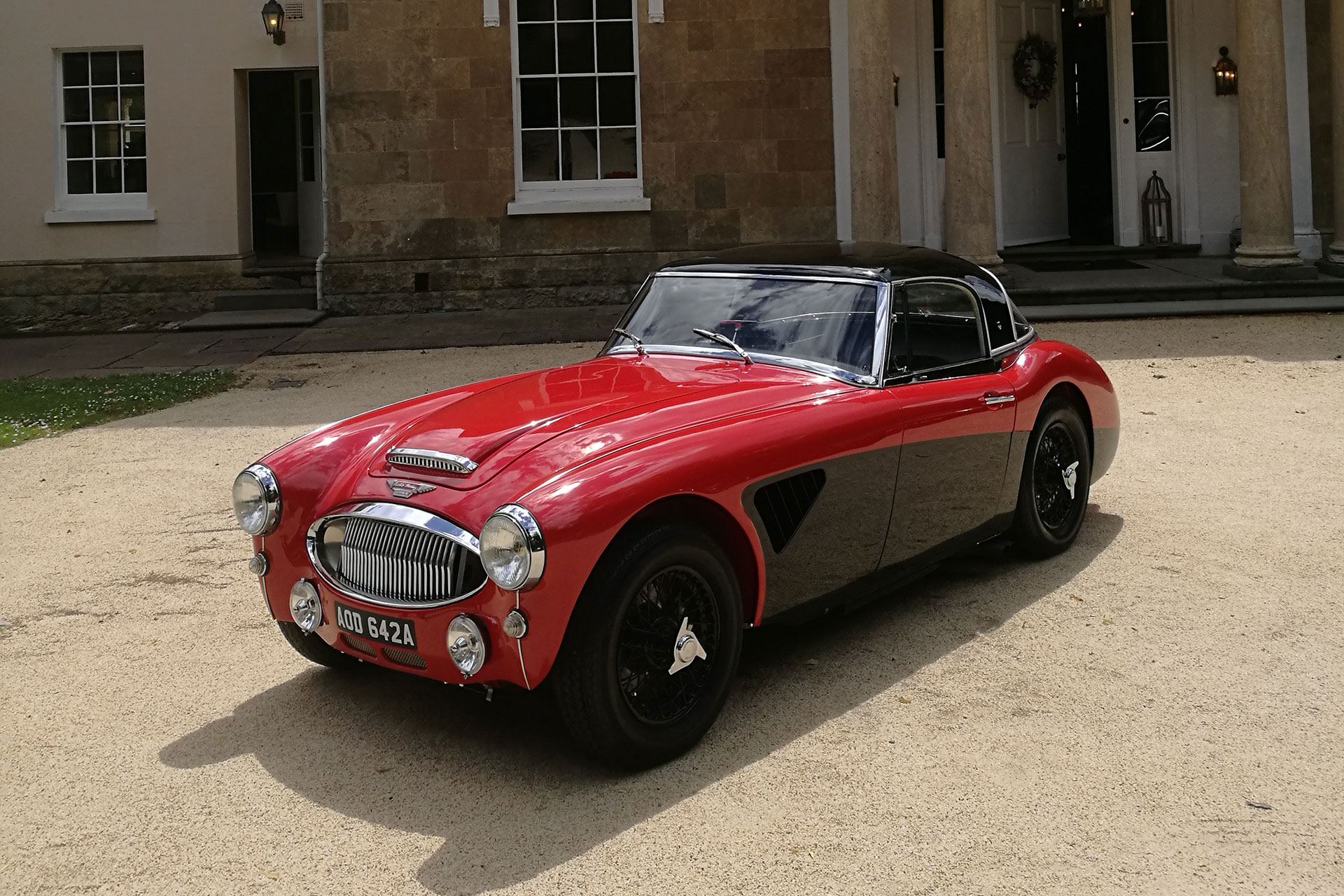 Red Austin Healey 3000 BJ7 side view in front of Georgian house